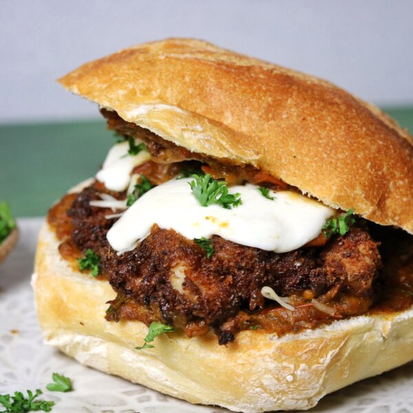 A spicy fried chicken sandwich topped with mozzarella cheese and a homemade tomato sauce